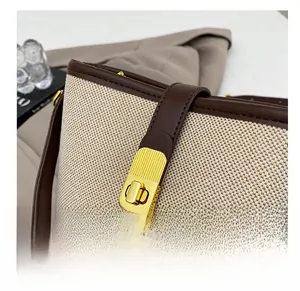 Detail of golden metal twist lock on beige woven and brown leather shoulder bag