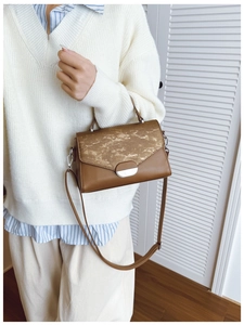Detail view of brown textured leather shoulder bag with metallic clasp and top handle