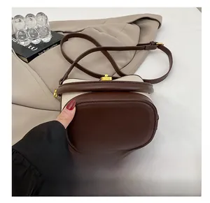 Detail of canvas and brown leather stitching with a gold metal clasp on a shoulder bag