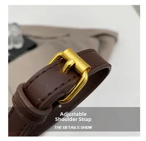 Detail showing the adjustable dark brown leather shoulder strap with gold metal buckle