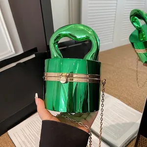 Emerald green acrylic cylinder evening clutch with melting gold handle and chain strap