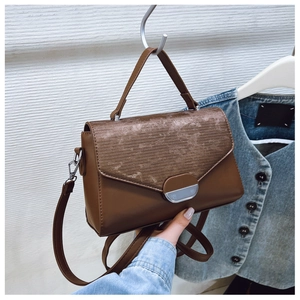 Detail of dark brown tote bag with vintage velvet texture flap and metal buckle closure