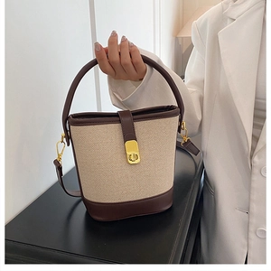 Detail of canvas bucket bag with leather trim and golden metal clasp closure