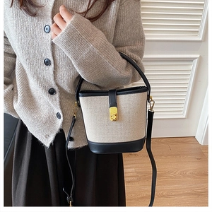 Close-up of canvas bucket bag with leather trim and gold CD embossed metal lock detail