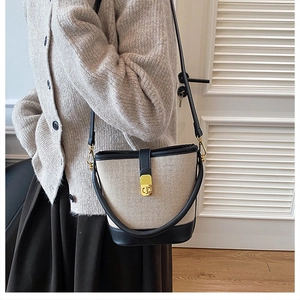 Detail of canvas bucket bag with black leather trim and golden metal CD logo clasp