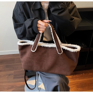 Detailed view of dark brown suede tote bag with white faux lamb wool trim and shoulder strap