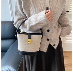 Detailed view of canvas bucket bag featuring black leather trim and golden metal turn-lock
