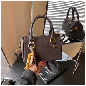 Detail der dunkelbraunen Boston Bag mit goldener Hardware und Perlen-Accessoire
