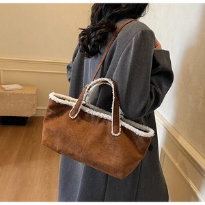 Detail of suede tote bag with faux shearling trim worn over a grey autumn coat