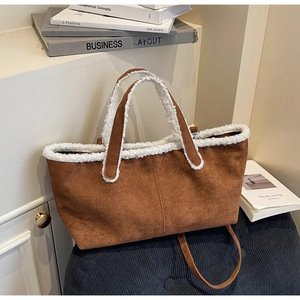 Detail of suede tote bag with white faux shearling trim on a blue corduroy cushion