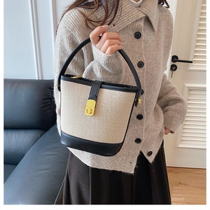 Detail of two-tone bucket bag featuring beige woven texture and black leather trim