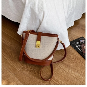 Detail of vintage canvas and brown leather bucket bag with golden metal buckle and strap