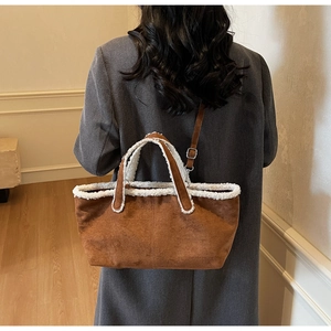 Brown suede tote bag with white faux shearling trim shown on a person in grey coat