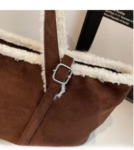 Detail of adjustable shoulder strap and silver buckle on brown suede tote with faux shearling