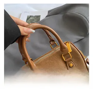 Detail der braunen Boston-Tasche aus Leder mit Litschi-Muster und edlen goldfarbenen Beschlägen