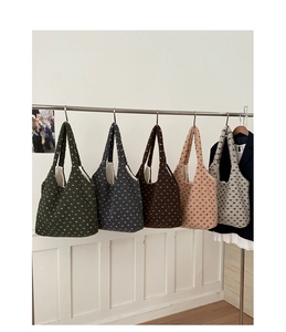 Detail of five plush heart-patterned tote bags in various colors hanging on a metal rack