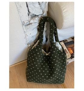 Detail of green sherpa shoulder bag with white polka dots on a textured background