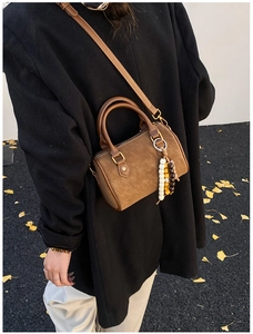Braune Zylinder-Eimertasche aus Wildleder mit Perlenanhänger am Model draußen