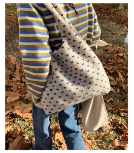 Detail of white plush shoulder bag featuring blue star patterns and soft lamb wool texture