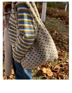 Detail of soft cream sherpa tote bag featuring blue star patterns in a fall outdoor setting