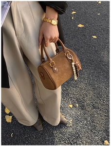 Details einer braunen Zylindertasche mit Retro-Perlenanhänger in Herbststimmung