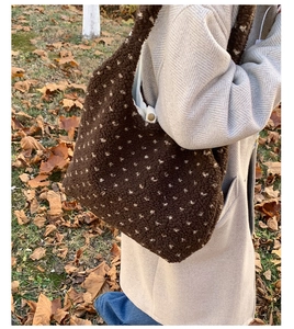 Detailed texture of brown plush shoulder bag with white polka dots on autumn grass