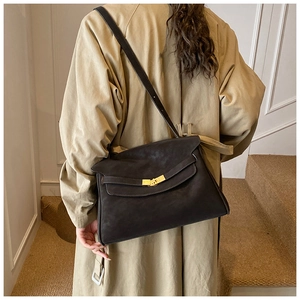 Détail d'un sac cabas rétro en cuir souple avec fermoir rotatif doré sur le rabat latéral