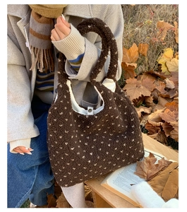 Detailed shot of dark brown plush tote bag with white heart patterns and metal snap closure