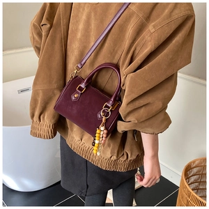 Nahaufnahme einer burgunderroten Mini-Boston-Tasche aus Leder mit schicken Perlenanhängern