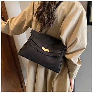 Détail d'un sac cabas vintage en cuir noir avec boucle dorée et sangle décorative