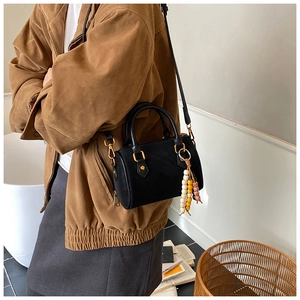 Detailansicht der schwarzen Mini-Boston-Tasche aus mattem Leder mit Perlenanhänger