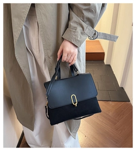 Detail of black patchwork shoulder bag with golden U-shaped buckle and leather top handle