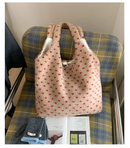 Detail of plush tote bag with red floral patterns showing soft texture and metal clasp