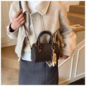 Detail der dunkelbraunen Leder-Bostontasche mit buntem Perlenanhänger und feinen Nähten