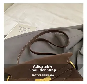 Détail de la bandoulière réglable et fermoir doré sur le sac cabas en daim marron