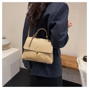 Detail shot of khaki leather and suede shoulder bag with gold U-shaped buckle on model