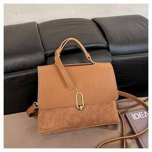 Detail of retro brown patchwork bag showing dual textures and gold oval twist lock
