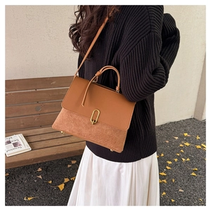 Detail of retro brown patchwork handbag with gold oval metal buckle and smooth leather