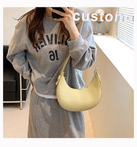 Pale yellow crescent shoulder bag styled with casual grey hoodie in a lifestyle mirror selfie