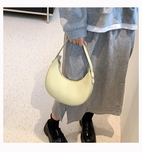 Close-up of a pale yellow crescent shoulder bag in premium smooth synthetic leather