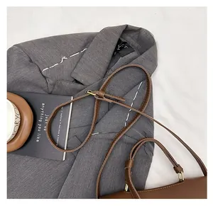 Detail view of the adjustable thin leather shoulder strap with gold metal buckle