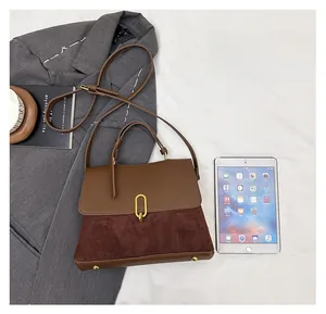 Top view of two-tone retro leather bag with gold buckle next to grey suit and tablet