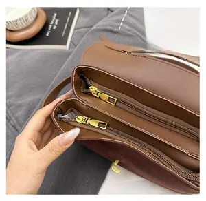 Detail view of the double zipper compartments with gold hardware on the brown tote bag