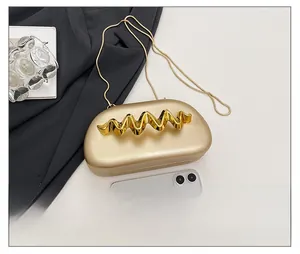 Macro shot of champagne gold evening clutch featuring a wavy handle and detachable chain