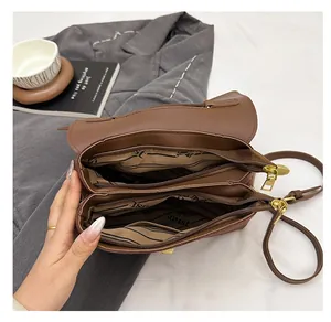 Detailed view of the brown shoulder bag's multi-compartment interior with gold zippers