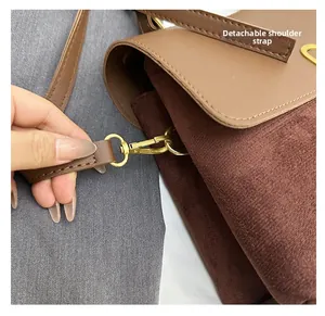Detail of a brown patchwork crossbody bag featuring a detachable golden metal strap