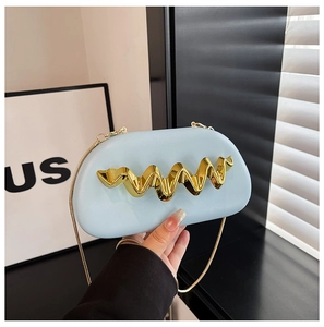 Detail of light blue shoulder bag featuring wavy gold hardware and a metallic chain strap