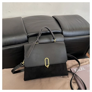 Detail of black crossbody bag featuring suede texture and gold oval twist lock closure