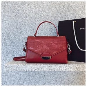 Minimalist red leather crossbody bag with silver hardware on a marble surface