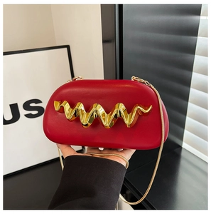 Close-up of a red leather clutch with a wavy gold metal trim and a slim chain strap
